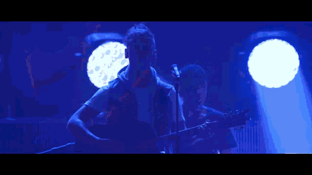 a man playing a guitar in front of a microphone