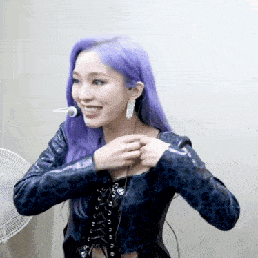 a woman with purple hair is smiling and adjusting her jacket