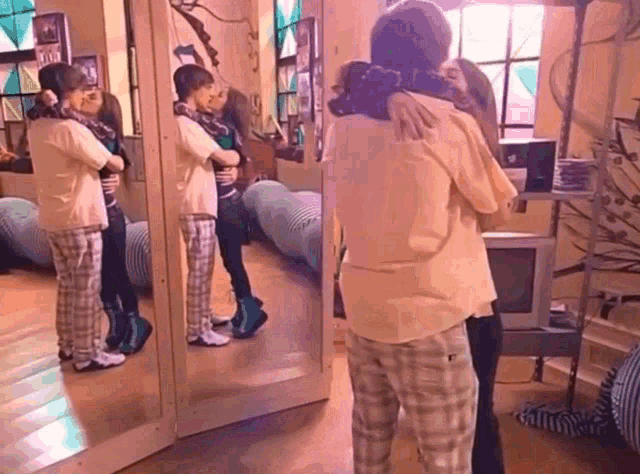 two people hugging in front of a mirror in a room