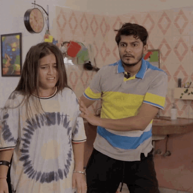 a man in a tie dye shirt stands next to a woman