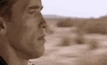 a close up of a man 's face in the desert looking at something .
