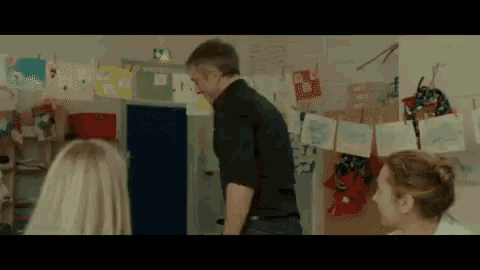 a man in a black shirt is standing next to a woman in a room with drawings on the wall