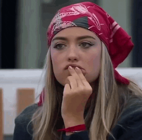 a woman wearing a red bandana and a red headband is holding her finger to her mouth .