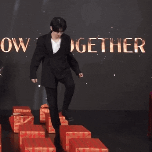 a man in a suit is standing on one leg in front of a sign that says w x t