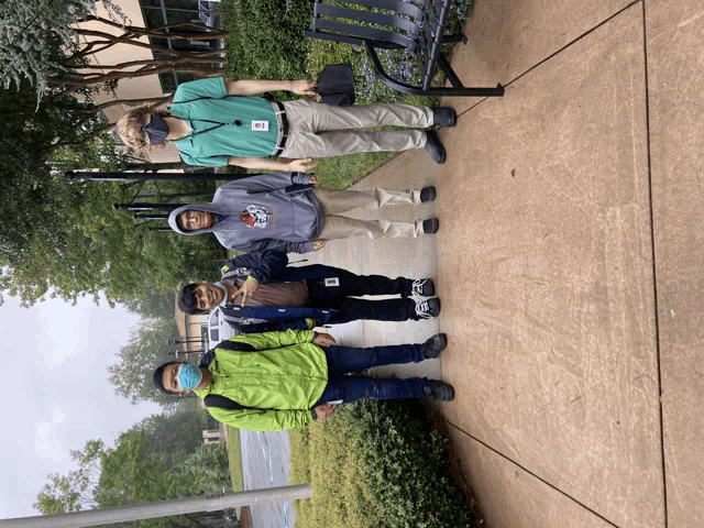 a group of people standing on a sidewalk with a man wearing a green shirt that says ' a ' on it