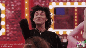 a woman with curly hair is making a face in front of a mirror .