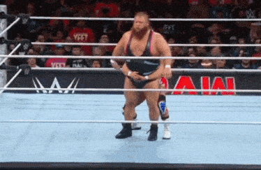 a wrestler is standing in a wrestling ring with a crowd watching .