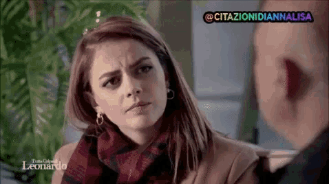 a woman wearing a scarf and earrings is sitting next to a man in a leonardo video