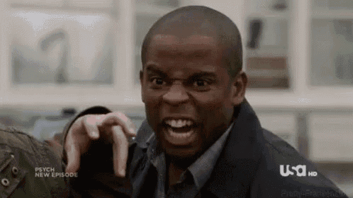 a man is making a funny face while pointing at another man .