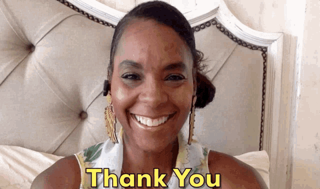 a woman is smiling in front of a bed with the words thank you above her