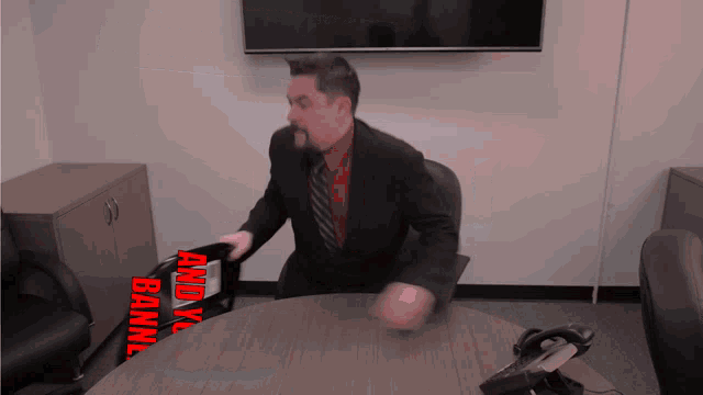 a man in a suit and tie is sitting at a table with a sign that says and you banned