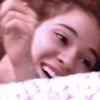 a close up of a woman laying on a bed with her mouth open and smiling .