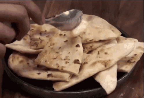 a person is taking a piece of bread with a spoon from a plate .