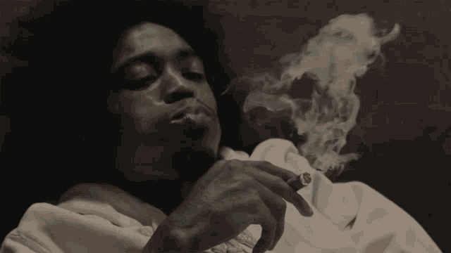 a man in a pink sweatshirt is smoking a cigar