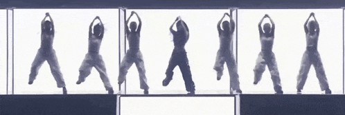 a group of people are dancing in front of a white wall