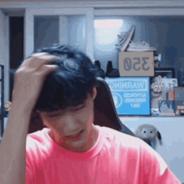 a man in a pink shirt is holding his head in front of a sign that says 022 .