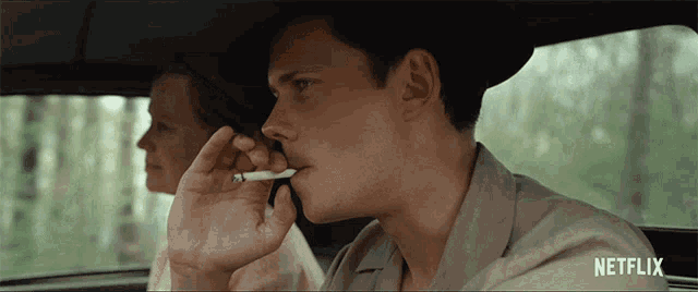 a man smoking a cigarette in a car with a netflix logo on the bottom