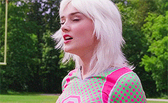 a woman with white hair is wearing a pink and green shirt with polka dots on it .