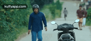 a man in a helmet is walking down a road next to a motorcycle .