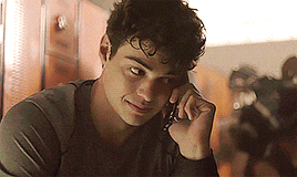 a young man is talking on a cell phone while sitting in a locker room .
