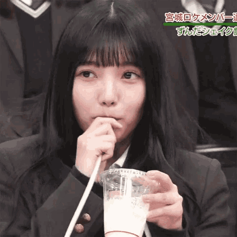 a girl is drinking a milkshake with a straw in a plastic cup with chinese writing on it
