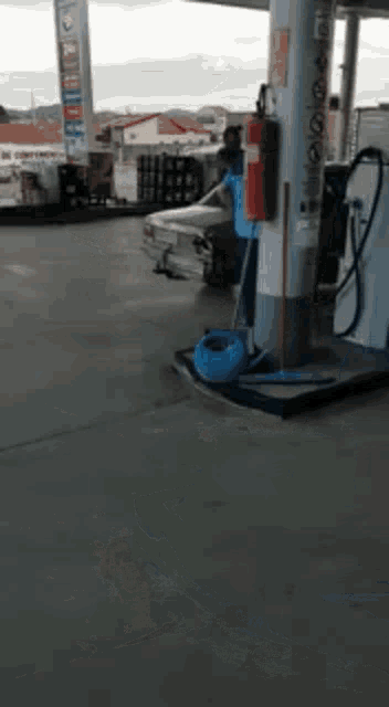 a man is standing next to a car at a gas station
