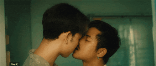 a couple of men kissing in front of a screen that says play ( n)
