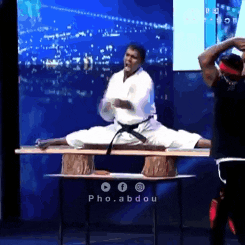 a man in a white karate uniform is sitting on a table
