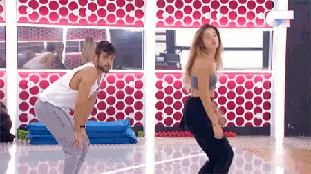a man and a woman are dancing in front of a mirror in a gym .