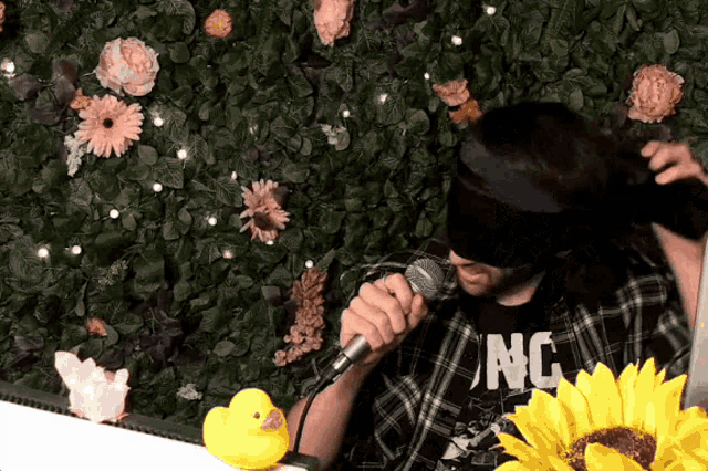 a blindfolded man singing into a microphone with a shirt that says nc on it