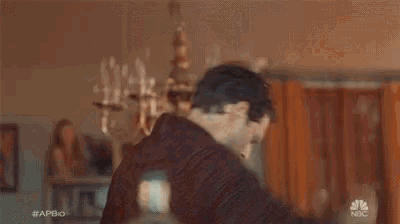 a man is standing in front of a chandelier holding a cell phone in his hand .