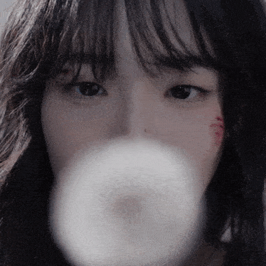 a close up of a woman 's face with a white object in her mouth