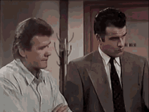 two men in suits and ties are standing next to each other in an office .