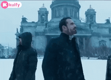 a group of people standing in front of a large building in the snow .