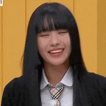 a girl with long black hair is wearing a school uniform and tie and smiling .