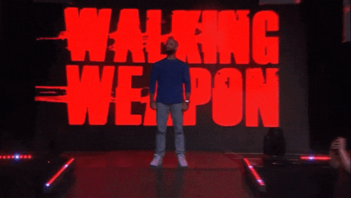 a man is standing in front of a screen that says walking weapon