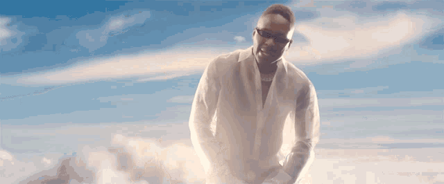 a man in a white shirt and white gloves is standing in the sky