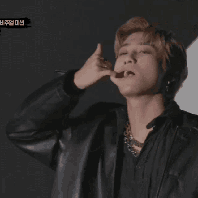 a man wearing a black jacket is making a hand sign