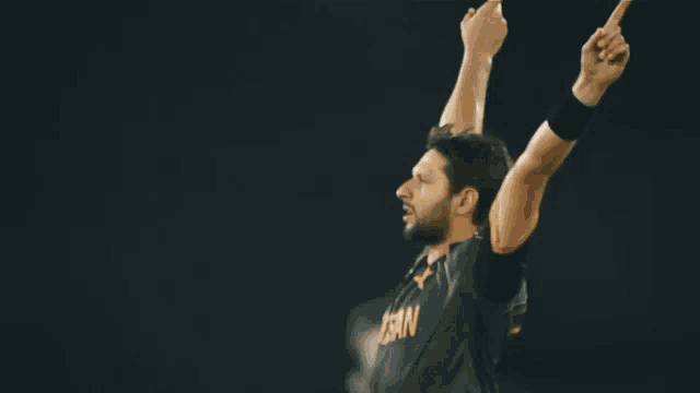 a man in a pakistan jersey holds up his arms in the air