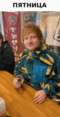 a man in a colorful jacket is sitting at a bar holding a glass of wine