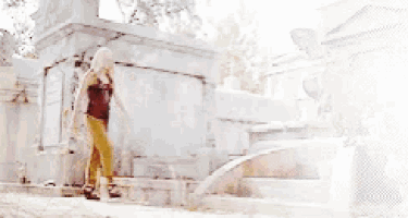 a woman in a red tank top is walking down stairs in a cemetery .