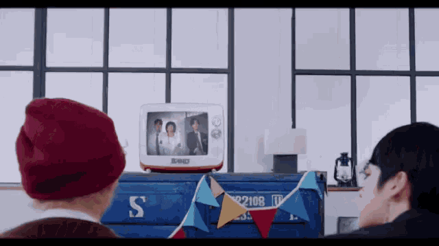 a man in a red hat is looking at a tv with a picture of a family on it