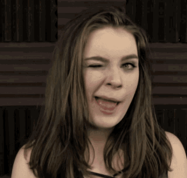 a woman with long brown hair is making a funny face with her tongue out