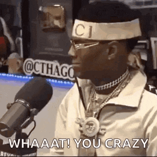 a man wearing a gucci headband and glasses is talking into a microphone .