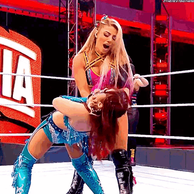two women are wrestling in a ring with the letter a on the wall