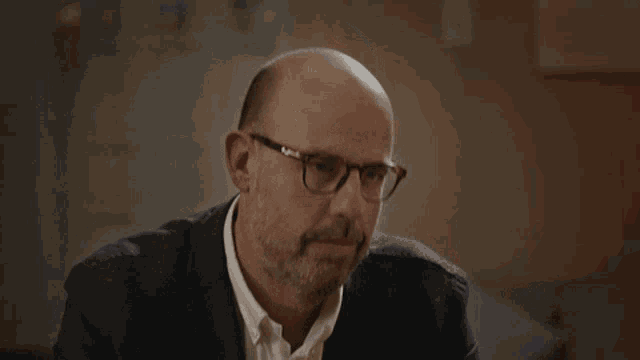 a man wearing glasses and a suit looks down