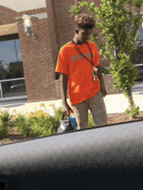 a man in an orange shirt is holding a blue bag