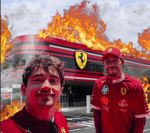 two men standing in front of a ferrari building with flames behind them
