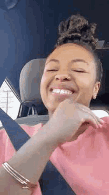 a woman is sitting in the driver 's seat of a car and smiling .