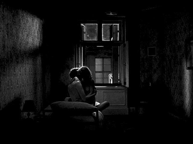 a black and white photo of a man and woman kissing